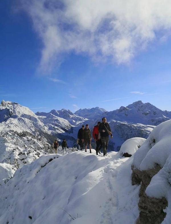 Vänner går på rad längs en snöig bergstopp.